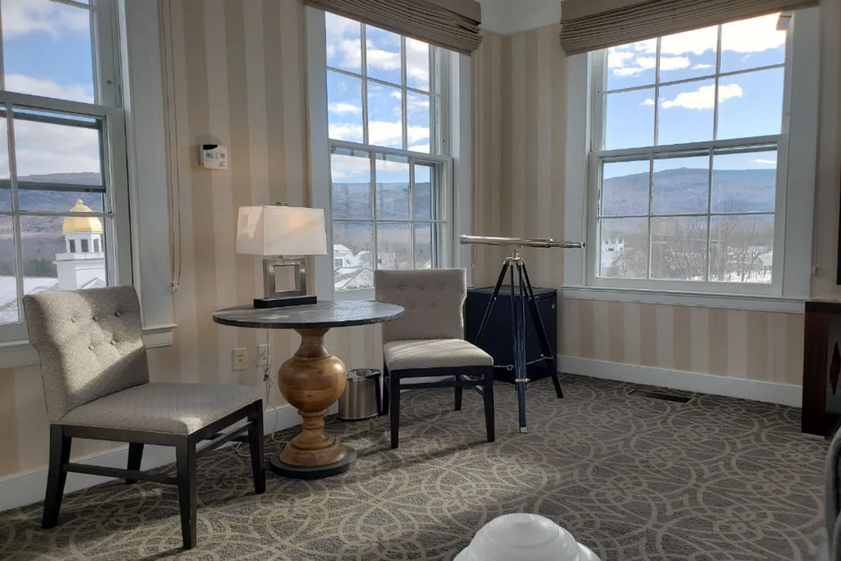 A tranquil cupola setting with a telescope, a round table flanked by chairs, and windows all around the space. The ambiance is serene and reflective, offering the ideal spot to take in sunsets or gaze at the mountains from a private observatory perch.